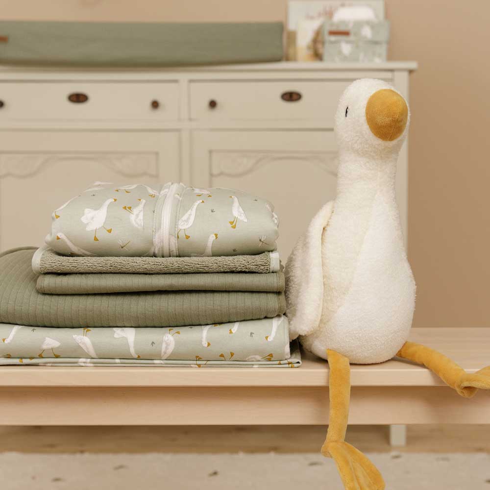 Der Little Dutch-Sommer-Schlafsack "Little Goose" liegt neben dem gleichnamigen Plüschtier gefaltet auf einem Tisch.